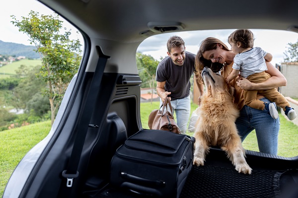 family of three with their dog getting into a car